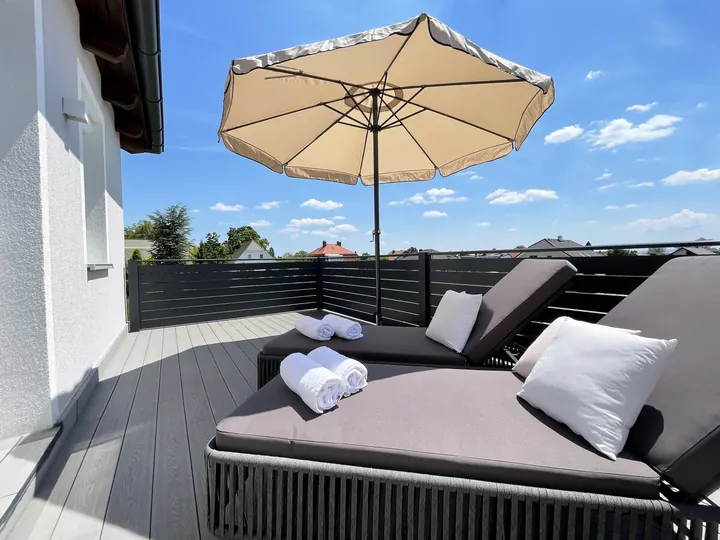 Sonnenliegen und Sonnenschirm auf dem Balkon