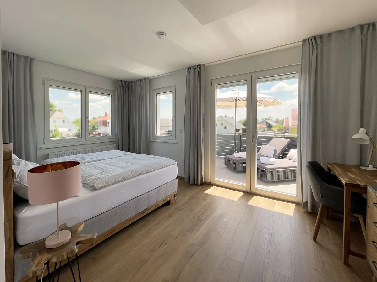 Sonniges Schlafzimmer mit Boxspringbett und Zugang zum Balkon von Haderer’s Home
